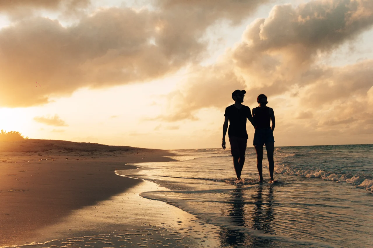 Un couple marchant sur la plage au coucher du soleil