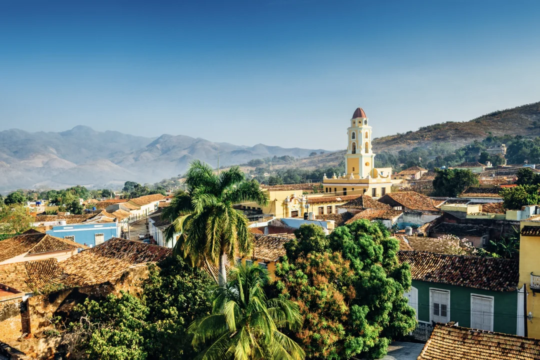 Vue panoramique de la ville de Trinidad, Cuba, avec des montagnes en arrière-plan et un ciel bleu. Le clocher appartient à l'église et au couvent de San Francisco.